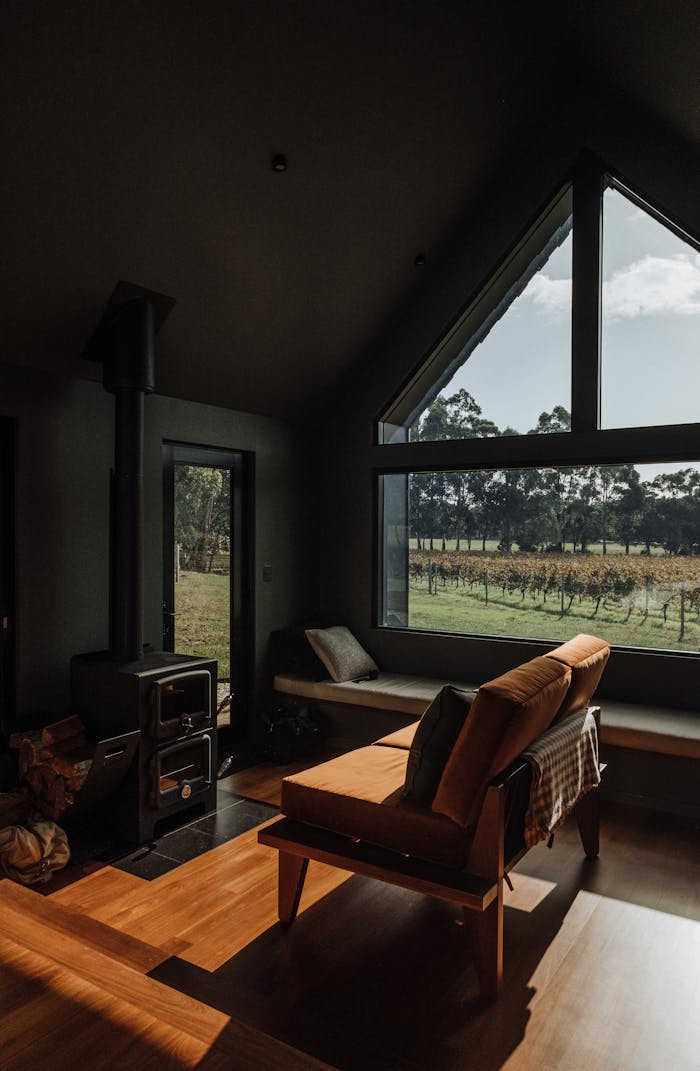 Home A warm, inviting living room with a fireplace and large window overlooking nature.